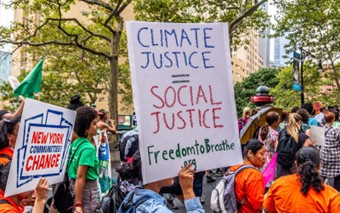 A handmade protest sign reads "climate justice = social justice" and "Freedom to Breathe." 