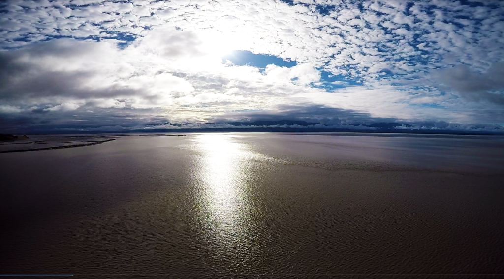 Sun reflecting on the ocean and thin white clouds in the sky.