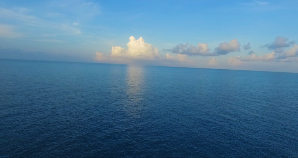 View of the calm blue Atlantic ocean with clouds above the horizon.