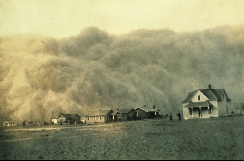 Image of a huge dust storm approaching behind a line of houses. 