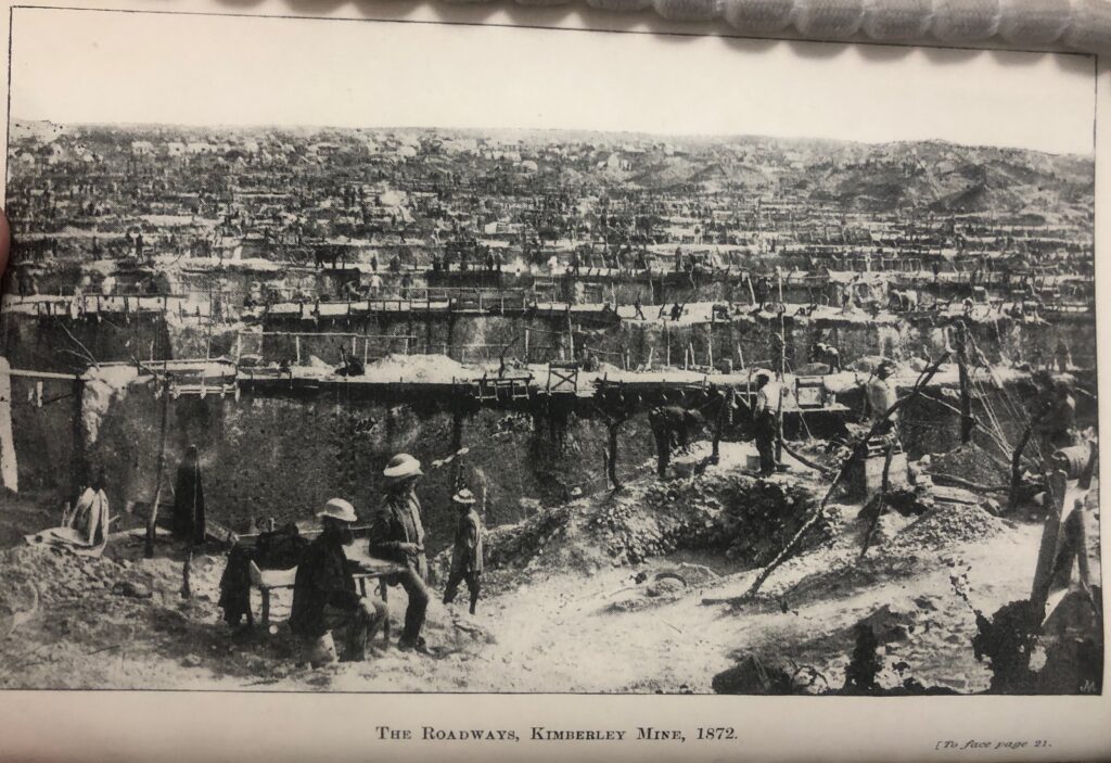 Photograph of a coal mine, featuring workers in the foreground. 